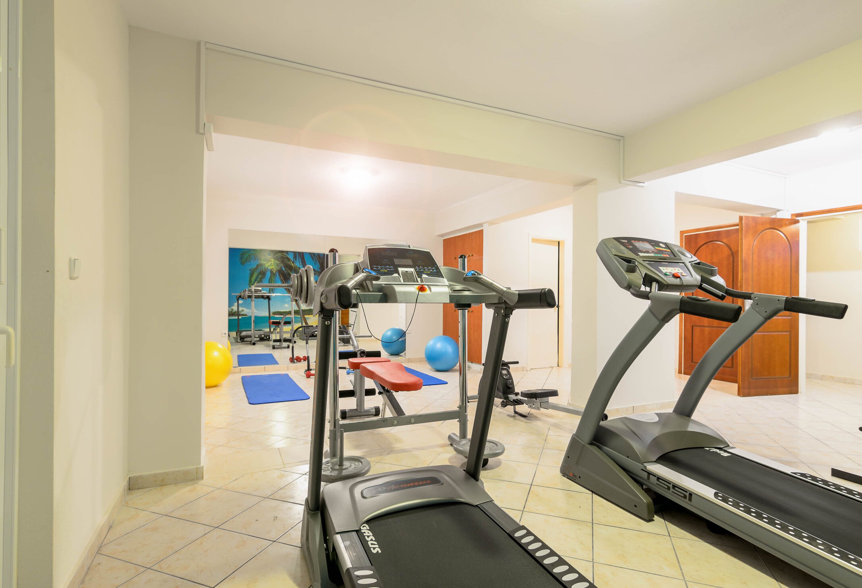 A home gym with treadmills, exercise balls, and a bench.