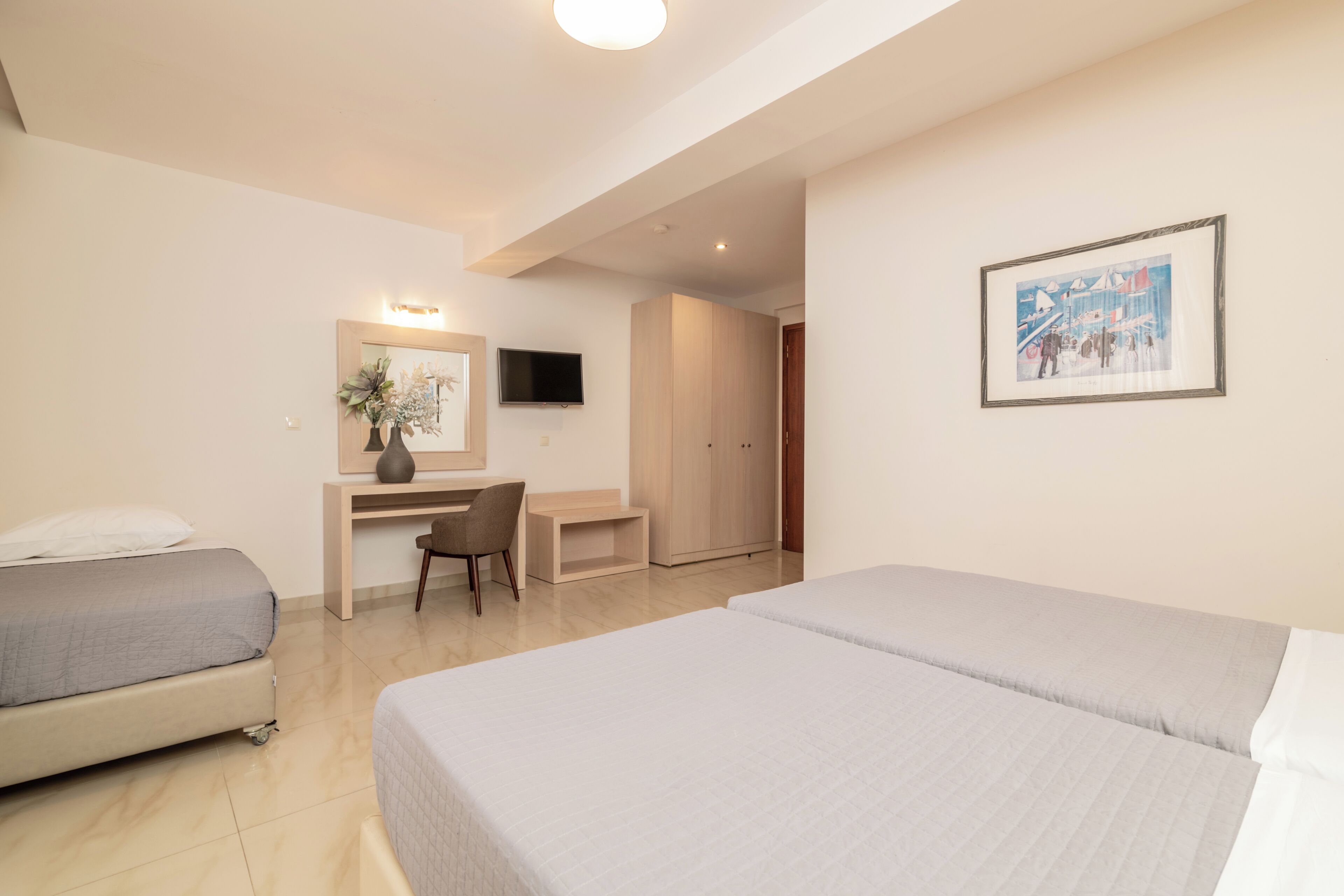 Une chambre d’hôtel comprenant un lit, un bureau, une chaise, une télévision et une armoire.