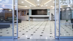 Un espace d’accueil comprenant un comptoir d’enregistrement, un coin salon avec des canapés et un sol carrelé.
