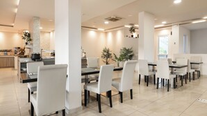 Un espace repas moderne avec des chaises blanches, une longue table et une cuisine en arrière-plan.