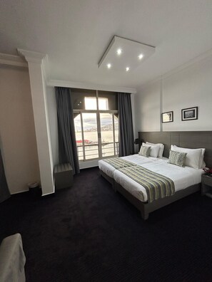 Habitación de hotel con una cama grande, vistas de un paisaje urbano a través de una ventana y un diseño moderno.