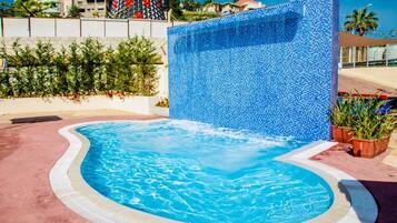 Una piscina al aire libre, sillones reclinables de piscina