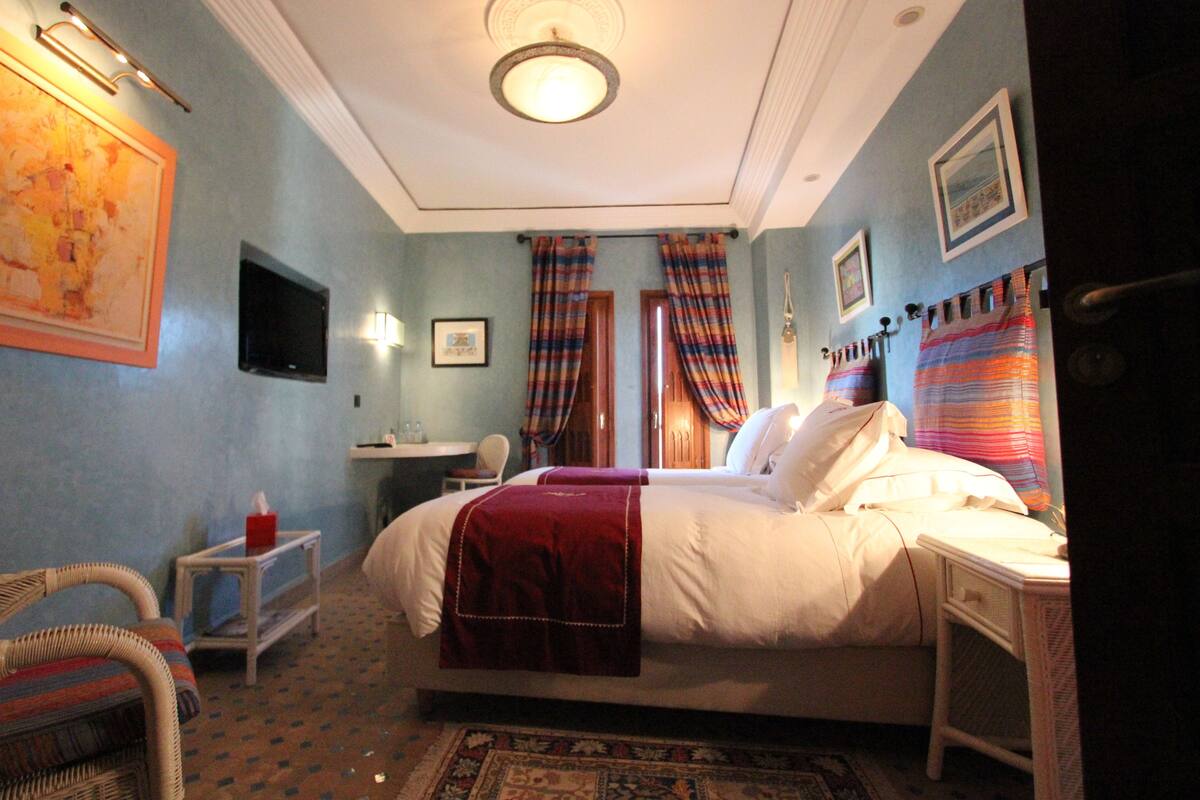 Habitación de hotel con una cama grande, un escritorio, una silla y un televisor en la pared.