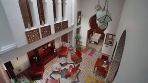 A spacious interior with a high ceiling, multiple seating areas, and a hanging light fixture. - Dar Chams Tanja (Tangier)