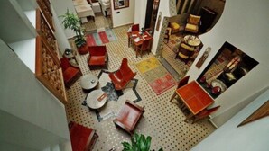A spacious living area with a high ceiling, a dining table, multiple chairs, a sofa, and a coffee table. - Dar Chams Tanja (Tangier)