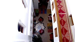 A narrow corridor with a patterned carpet, potted plants, and a large decorative rug. - Dar Chams Tanja (Tangier)