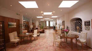 A spacious lobby with a high ceiling, multiple seating areas, and a tiled floor.