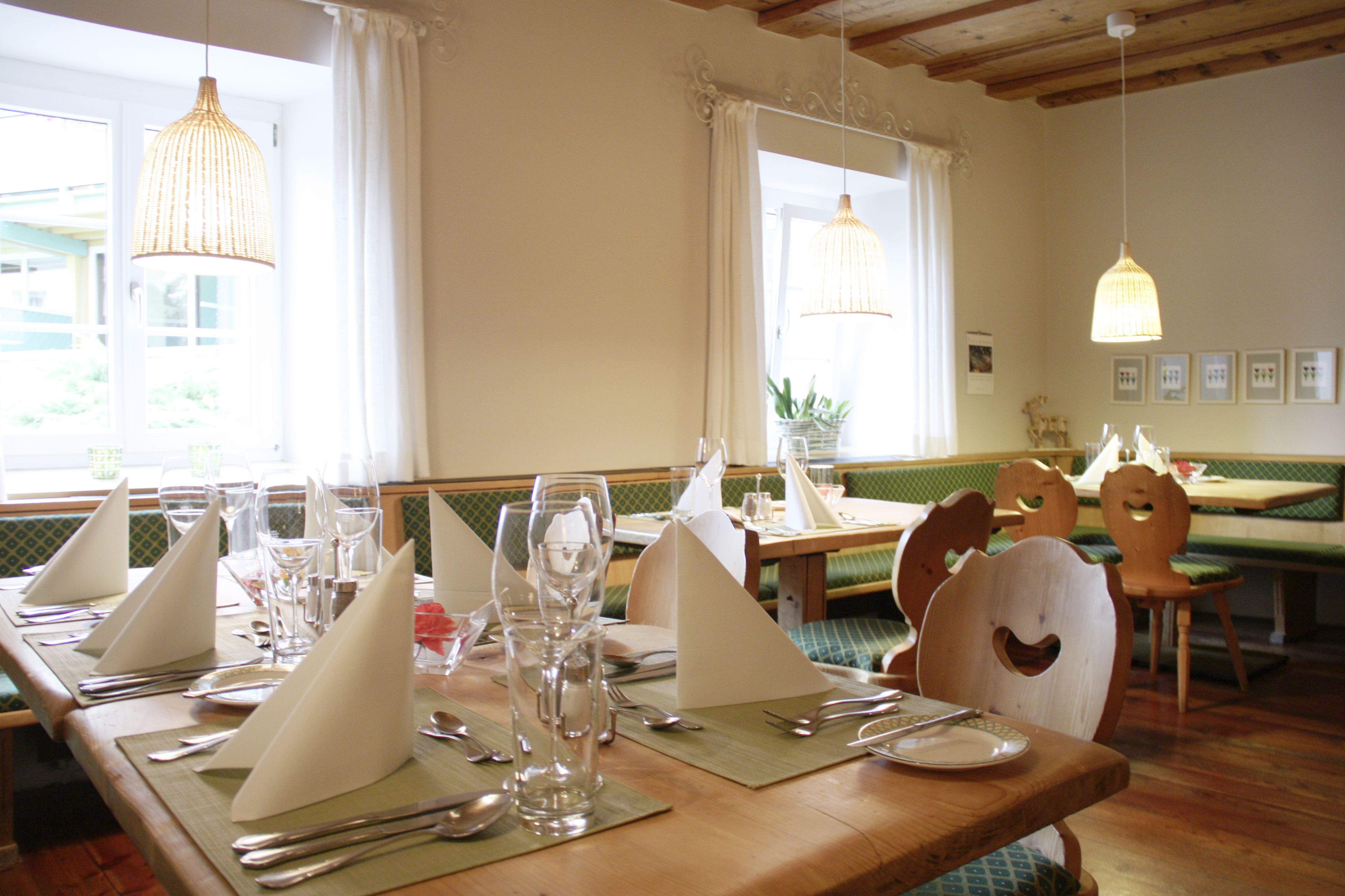 Un comedor con mesas de madera dispuestas para una comida, incluyendo cubiertos y cristalería.