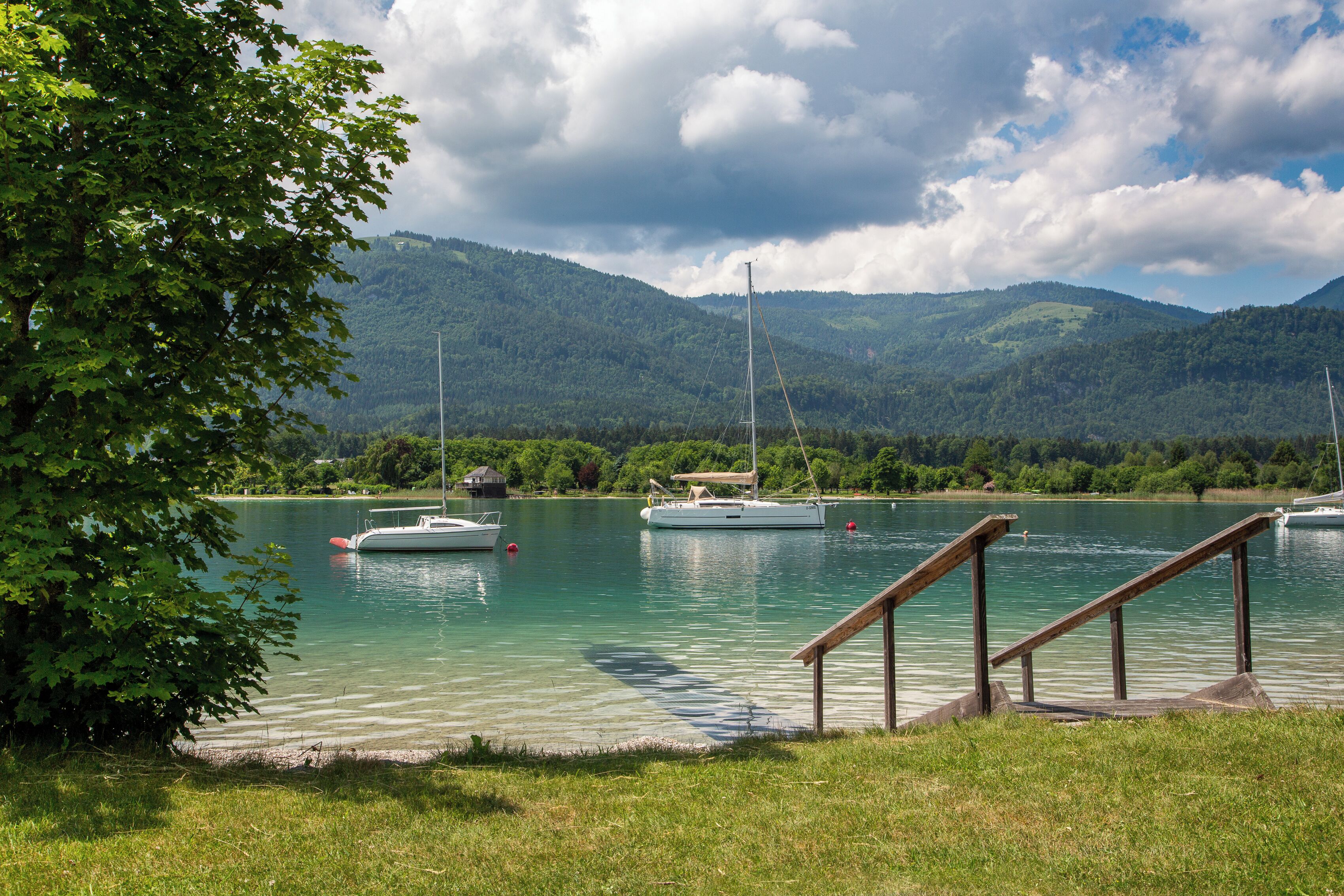 A lake with boats, a wooden dock, and mountains in the background.