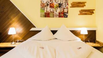 A hotel room with a bed, two bedside lamps, a wall art piece, and a wooden headboard.