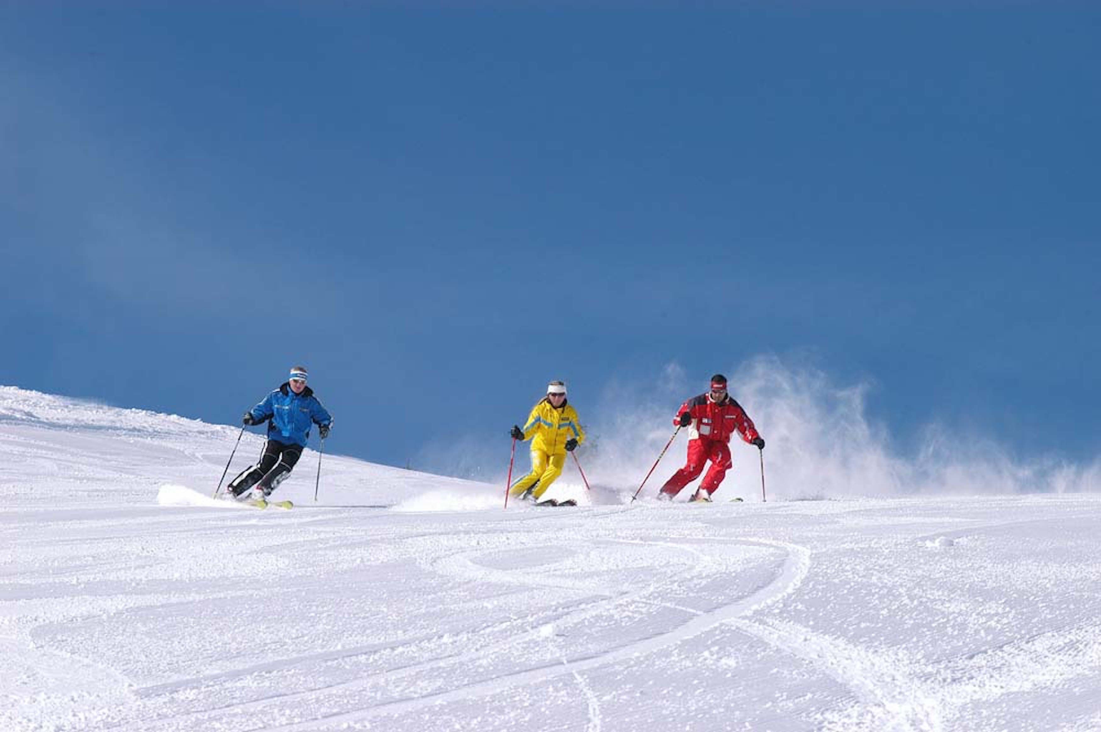 Three skiers on a snow-covered slope.