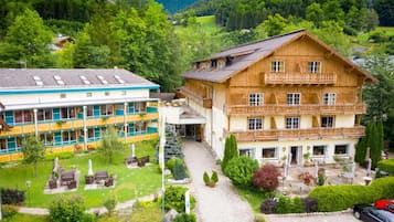 Situated in a serene valley, this hotel offers a traditional alpine-style facade and a balcony with a garden featuring outdoor seating.