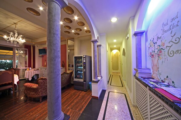 A hotel lobby with a dining area, a vending machine, and a reception desk. - Bed and Breakfast La Terrazza (Brescia)