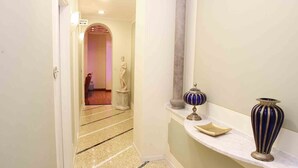 A hallway with a marble floor, a statue, and decorative vases on a shelf. - Bed and Breakfast La Terrazza (Brescia)