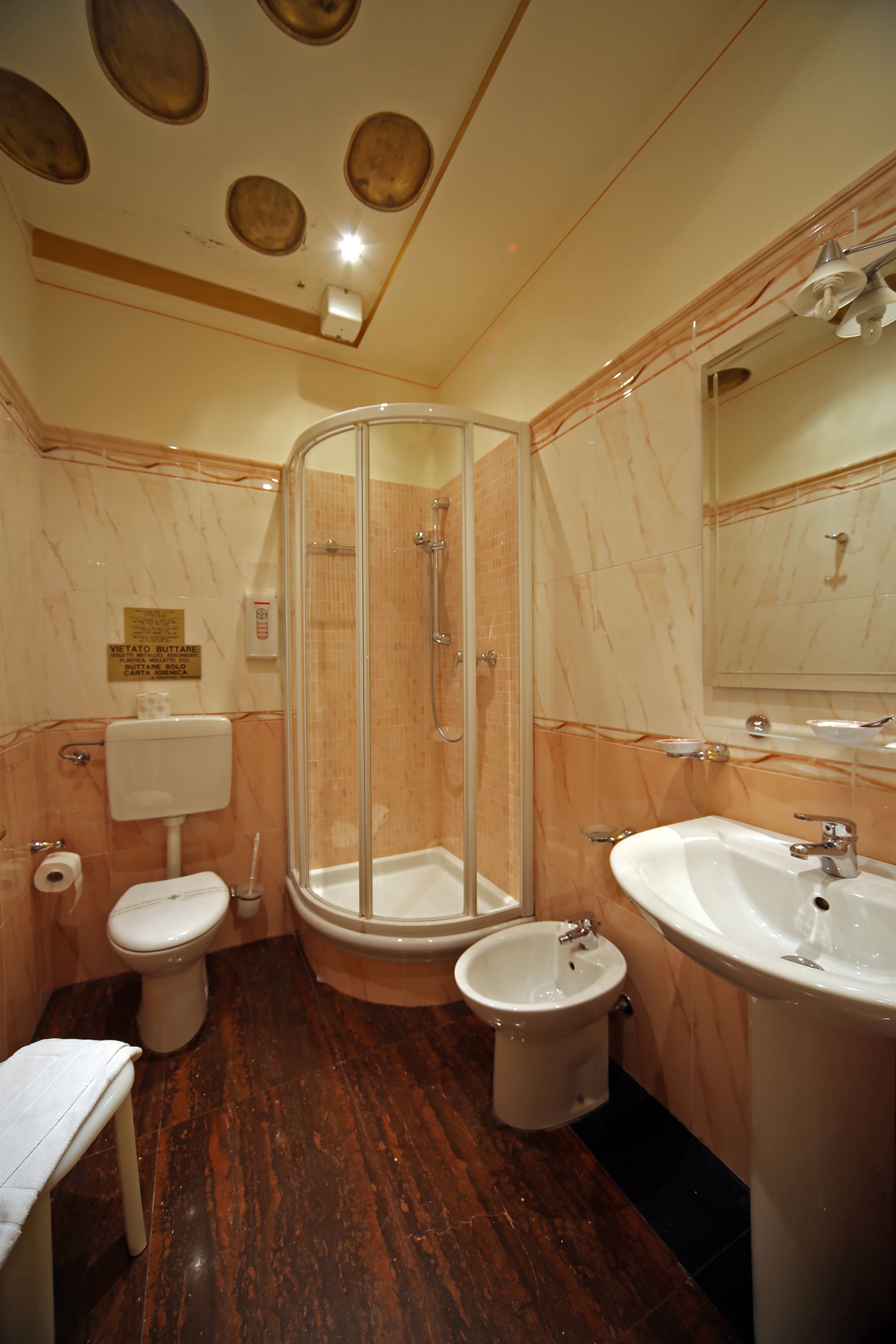 A bathroom with a glass-enclosed shower, a sink, and a toilet.