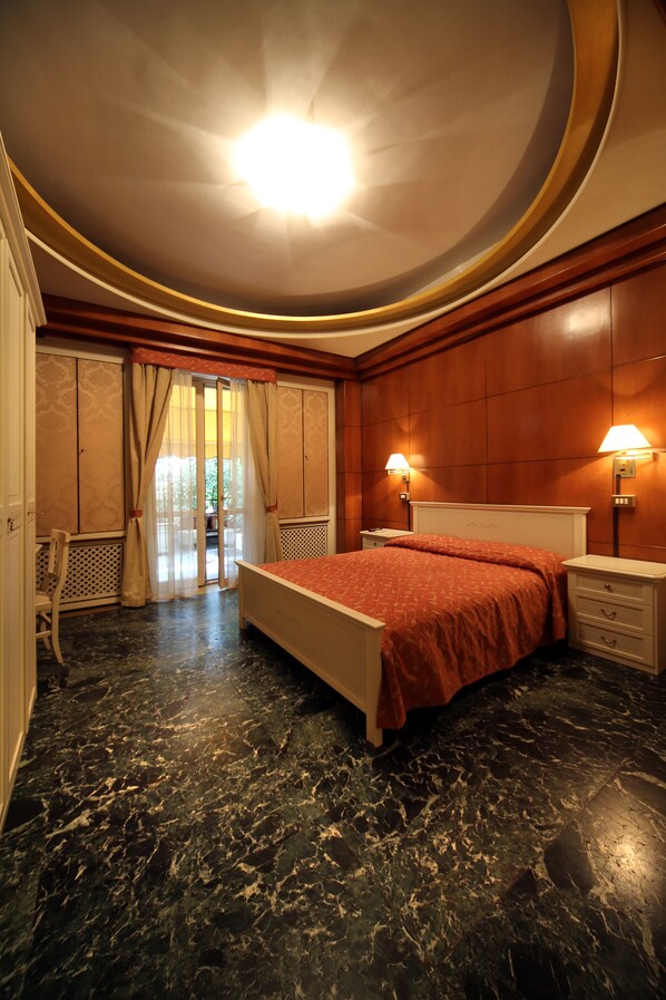 A bedroom with a bed, nightstands, a chair, and a window with curtains. - Bed and Breakfast La Terrazza (Brescia)