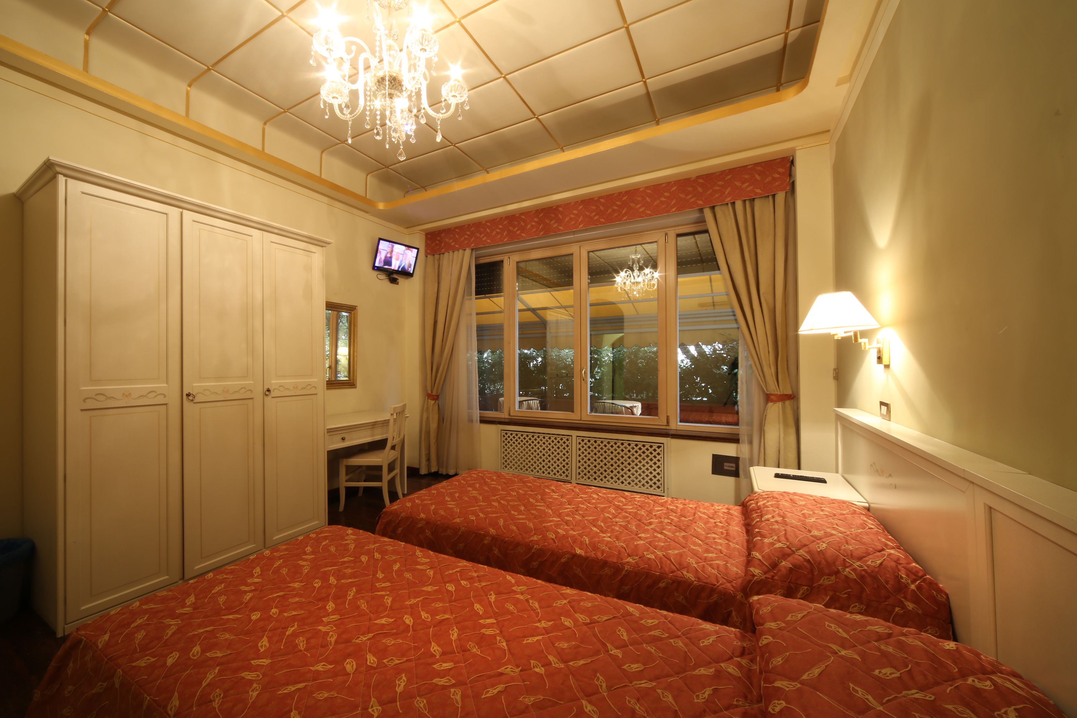 Een hotelkamer met twee bedden, een televisie, een bureau en een raam met gordijnen.