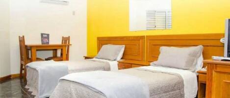 A room with two beds, a wooden headboard, a small table, and a television.