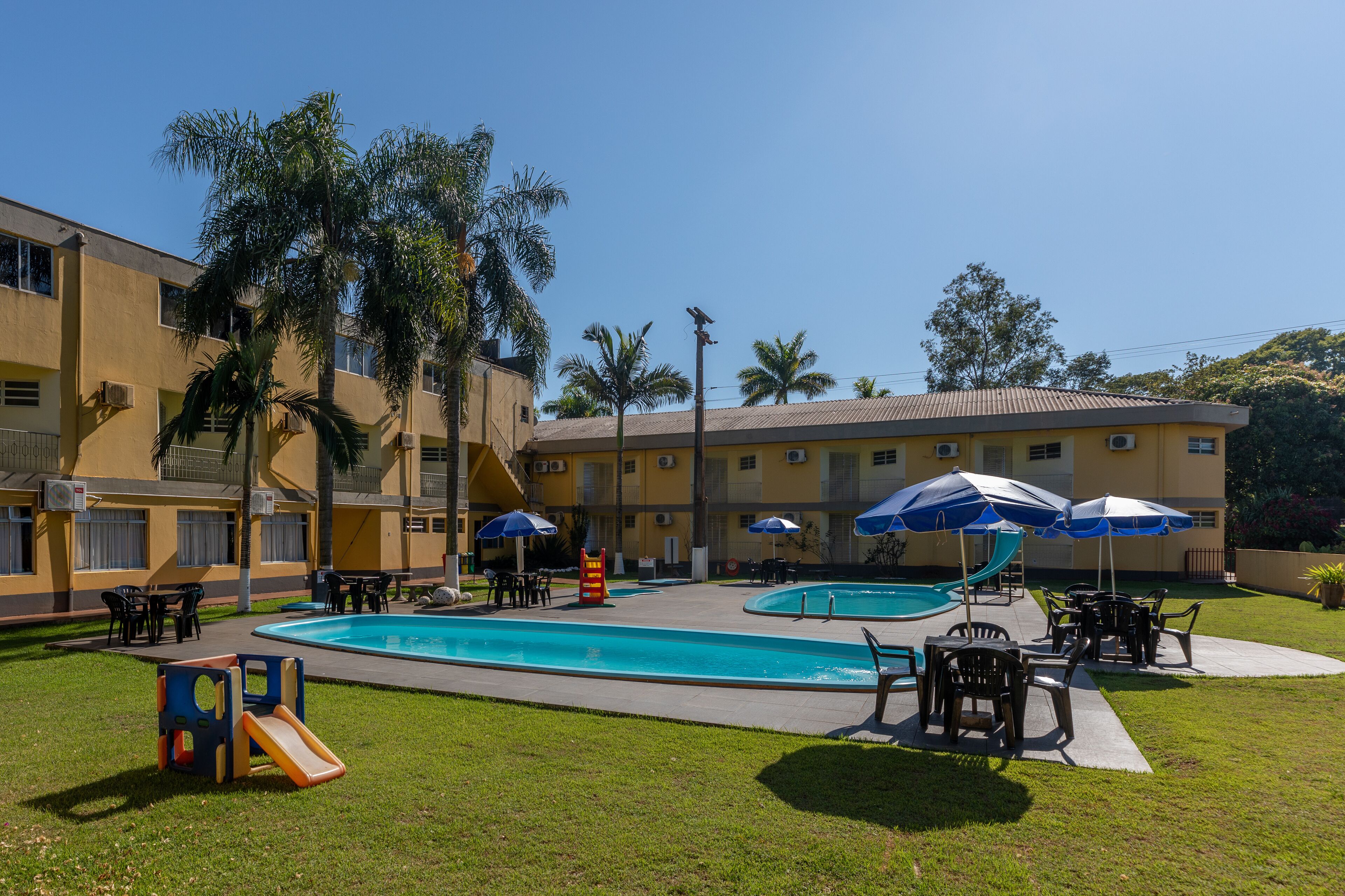 A pool area with a slide, umbrellas, and outdoor seating.