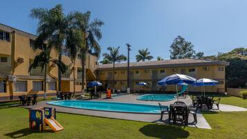 A pool area with a slide, umbrellas, and outdoor seating.