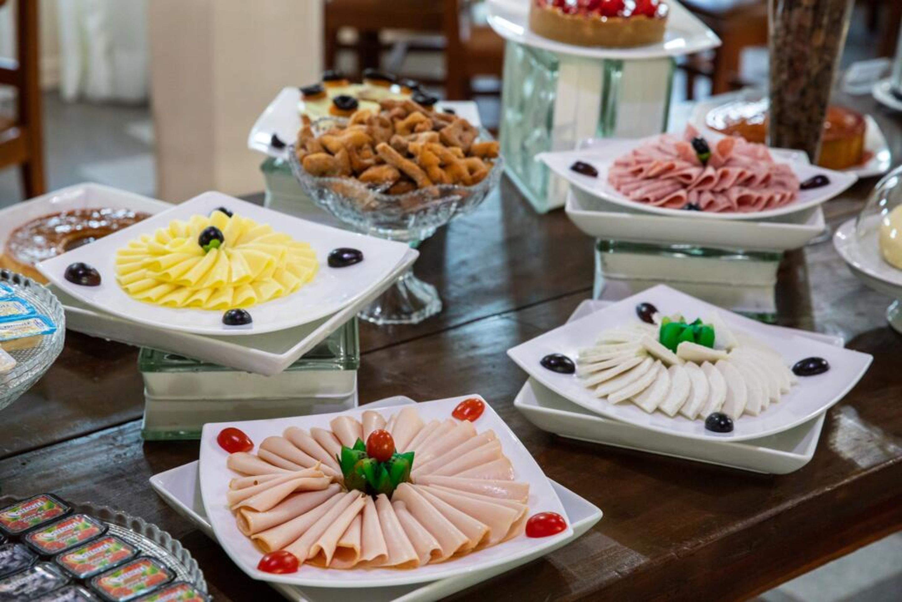 Una mesa de buffet con diversos alimentos, incluyendo una presentación de frutas amarillas, un plato de queso blanco y una variedad de embutidos.