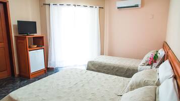 Habitación de hotel con dos camas, un televisor sobre un mueble de madera y un aire acondicionado en la pared.