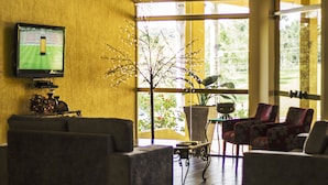 A living room with a television, a coffee table, and a potted plant. - Canzi Cataratas Hotel (Foz do Iguacu)