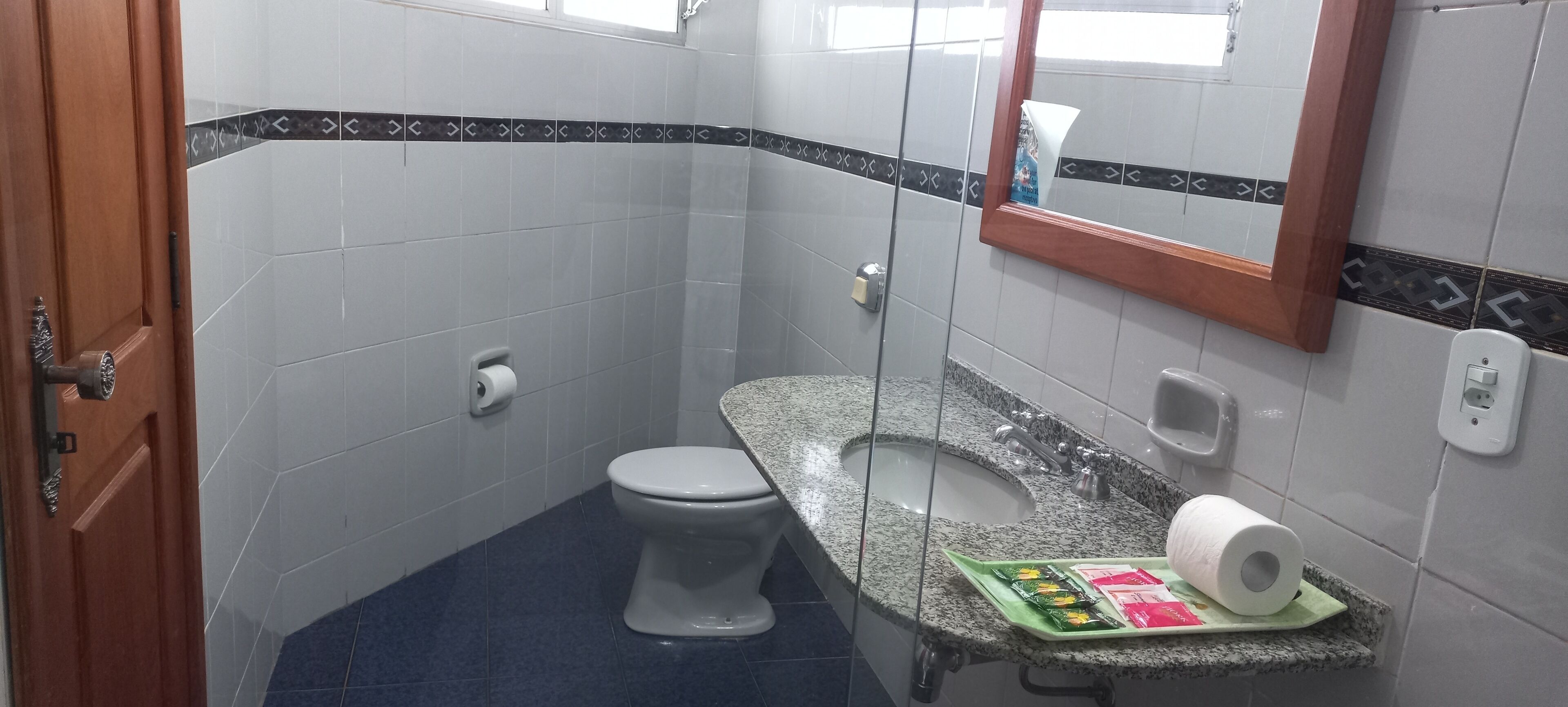 A small bathroom with a toilet, a sink with a marble countertop, and a mirror.