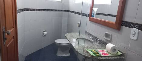 A small bathroom with a toilet, a sink with a marble countertop, and a mirror.