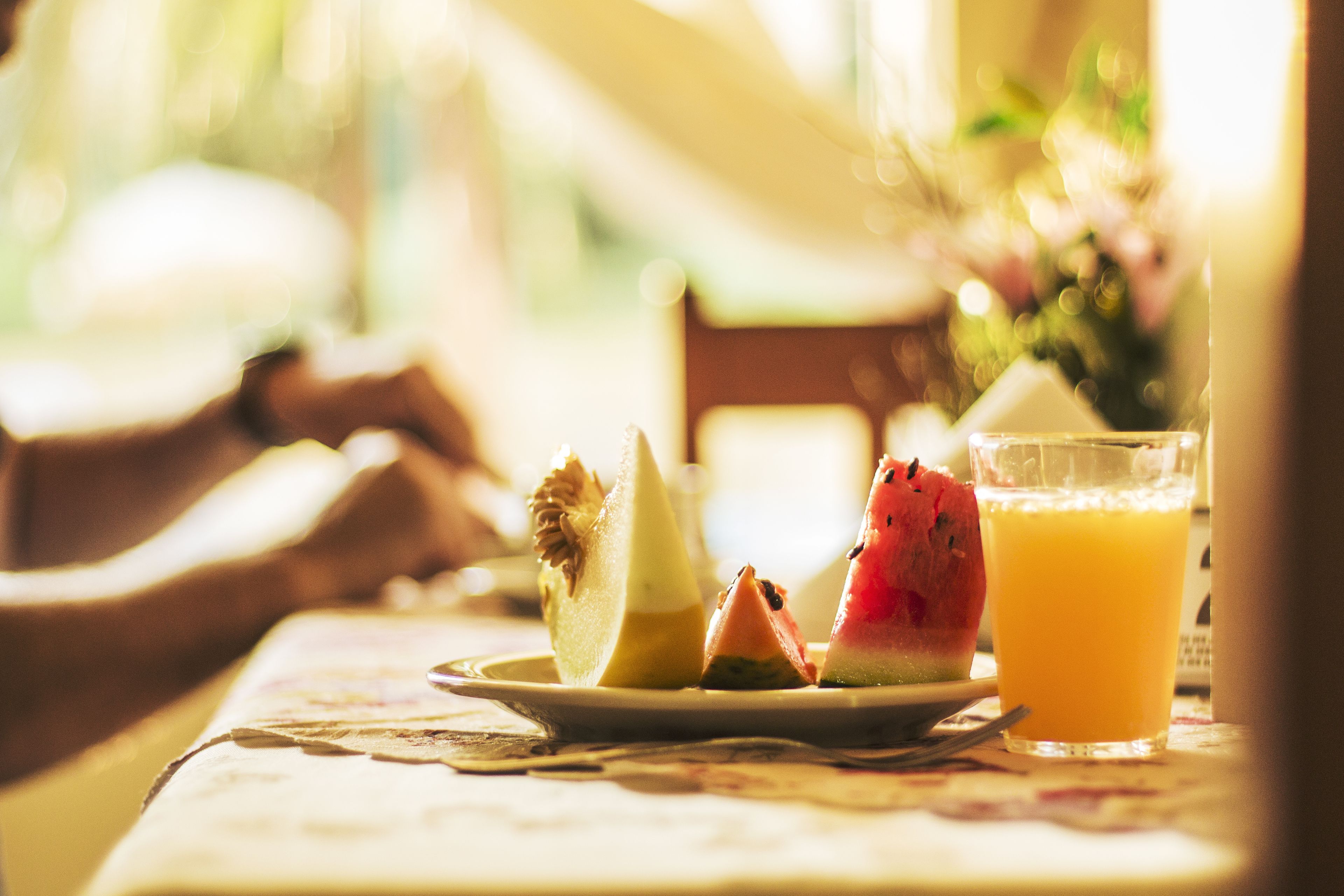 A breakfast setting with a plate of fruit and a glass of orange juice.