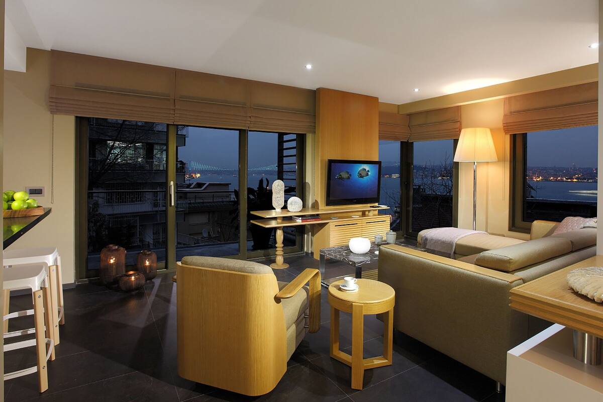 Una sala de estar moderna con un sofá, una mesa de centro, un televisor y vistas de la ciudad de noche.