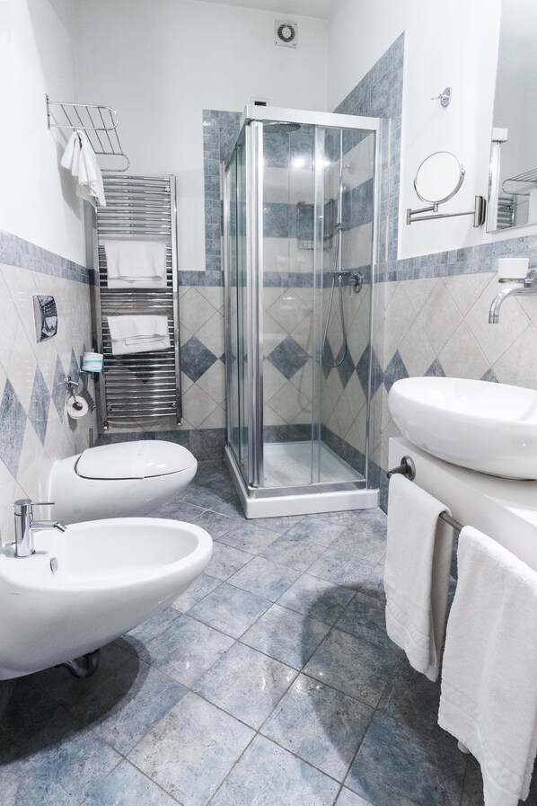 Une salle de bain moderne avec une douche à parois de verre, un lavabo blanc et un bidet.