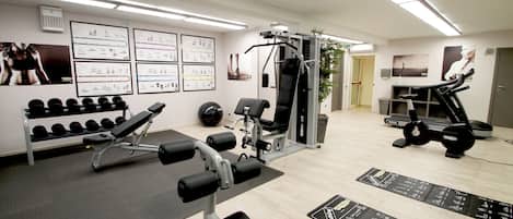 A gym with weightlifting equipment, treadmills, and exercise mats.