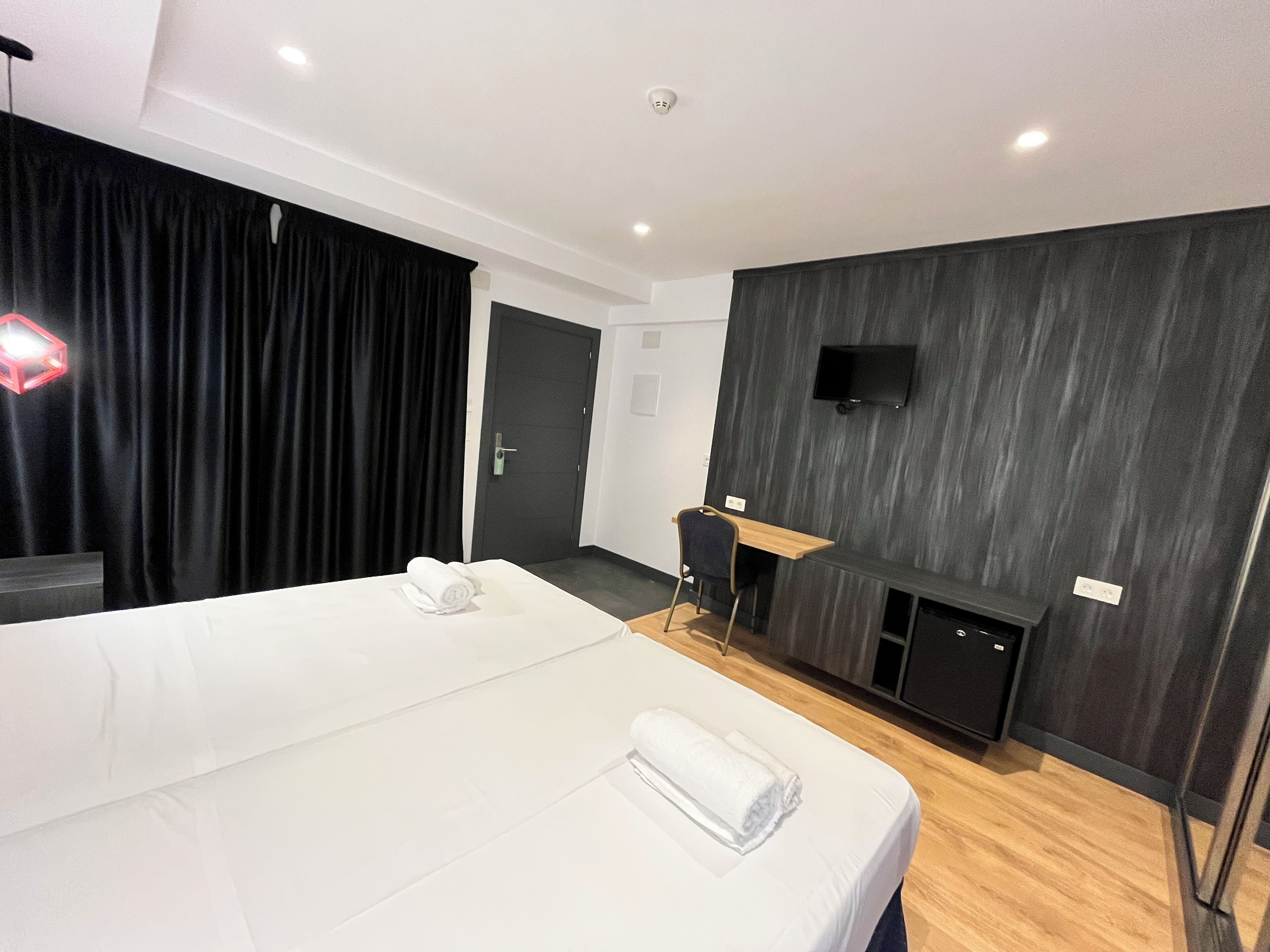 Ein modernes Hotelzimmer mit einem großen Bett, einem Schreibtisch, einem flachbildfernseher an der Wand und einem Kamin.