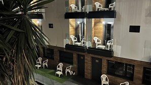 A hotel lobby with multiple seating areas, including outdoor and indoor spaces with white plastic chairs. - New "Villa Albero" Boutique (Torremolinos)