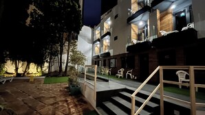 A modern building with a staircase leading to a balcony, surrounded by trees and outdoor seating. - New "Villa Albero" Boutique (Torremolinos)
