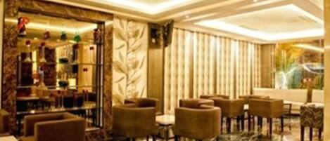 Un moderno vestíbulo de hotel con pisos de mármol, asientos cómodos y una zona de bar con botellas decorativas.