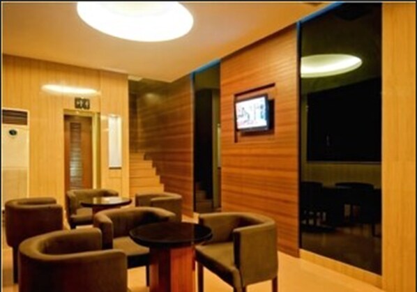Un moderno vestíbulo de hotel con paneles de madera, una escalera y zonas de estar.