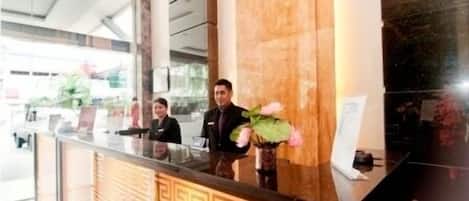 A reception desk with a marble column, a vase with flowers, and a modern interior design.