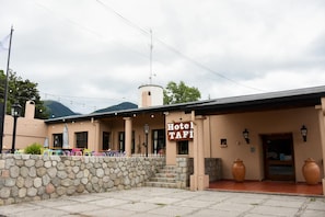 Un edificio con un letrero que dice "Hotel TAFI" y un muro de piedra en primer plano.