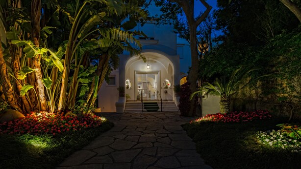 A well-lit pathway leading to a building with a white facade and arched entrance. - Villa San Felice (Capri)