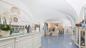 A spacious lobby with a high ceiling, a reception desk, seating area, and a bar. - Villa San Felice (Capri)