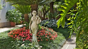 A garden with a statue, potted plants, and flowering bushes. - Villa San Felice (Capri)