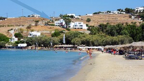 A beach with white buildings, a clear sky, and a calm sea. - Paros Paradise Apartments (Paros)