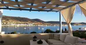 Una terraza con vistas a un pueblo costero, edificios blancos y barcos en el agua.