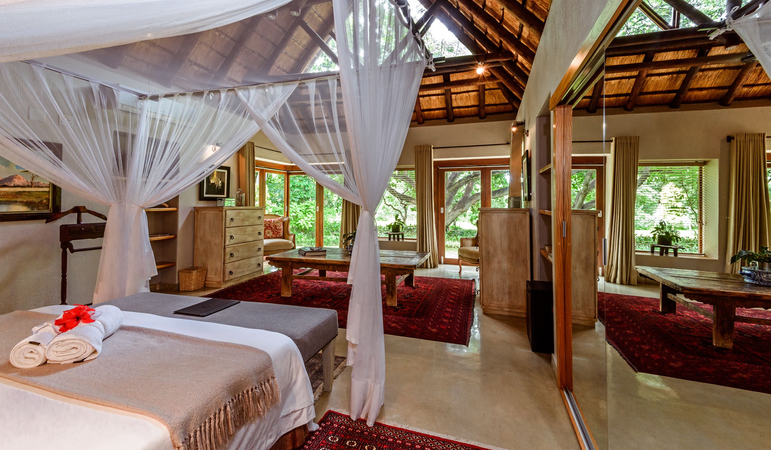 A room with a bed, a wooden desk, a chair, and a large window.