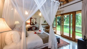 Une chambre spacieuse avec un grand lit, un baldaquin et une vue sur un jardin luxuriant, grâce à de grandes fenêtres.