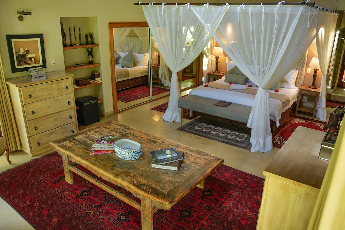 Ein Schlafzimmer mit einem Himmelbett, einem Holztisch, einem Schminktisch und einem Spiegel.
