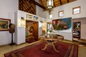 Eine geräumige Lobby mit einem runden Holztisch, Teppichen mit rotem Muster und gerahmten Kunstwerken an den Wänden.