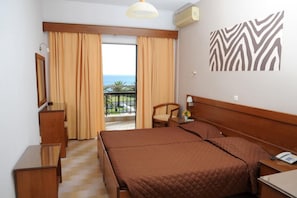 Una habitación de hotel con cama, una silla, un escritorio, un espejo y vista al mar.